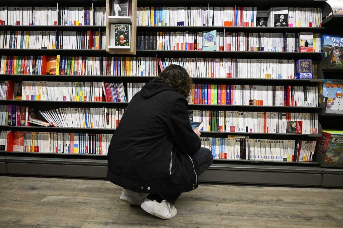 A woman looks at books in the library of a supermarket, in Bourgueil, on December 21, 2024. (Photo by Magali Cohen / Hans Lucas / Hans Lucas via AFP)